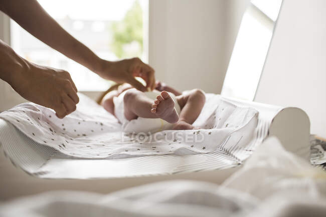Mother changing newborn baby son diaper on changing table — Stock Photo