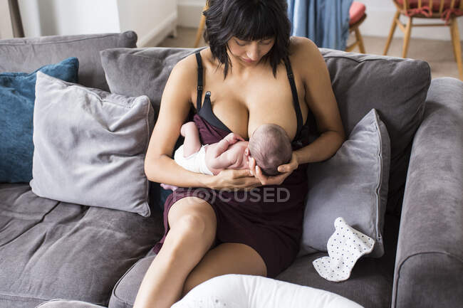 Mutter stillt neugeborenen Sohn auf Sofa — Stockfoto
