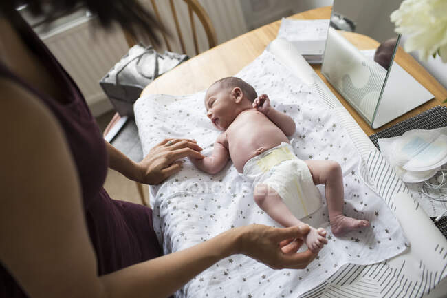 Mother changing diaper of newborn baby son on changing table — Stock Photo