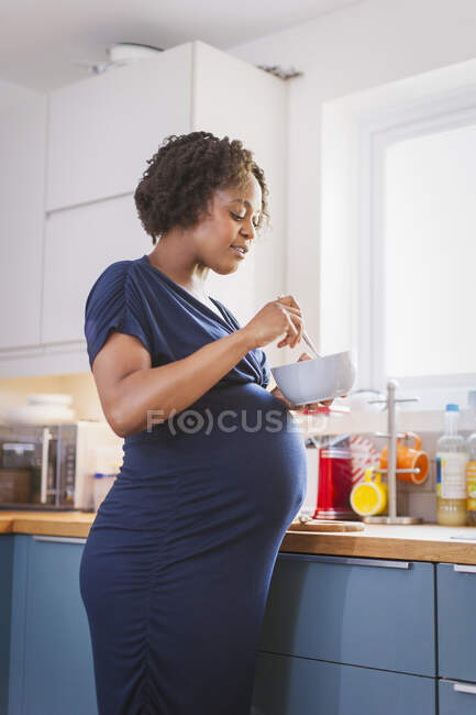 Беременная женщина ест на кухне — стоковое фото
