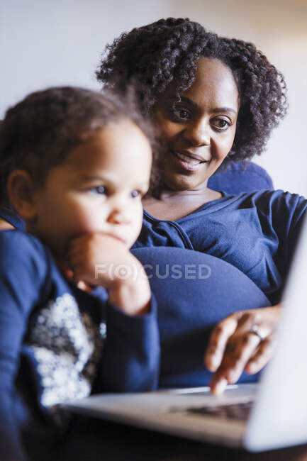 Schwangere Mutter und Tochter benutzen Laptop — Stockfoto