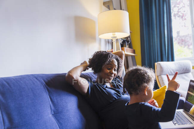 Вагітна мати і дочка використовують ноутбук на дивані — стокове фото
