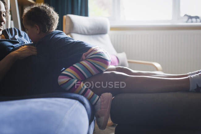 Cute curious daughter touching pregnant mother stomach on sofa — Stock Photo