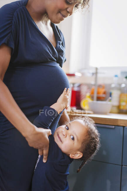 Портрет симпатичной дочери, трогающей живот беременной матери — стоковое фото