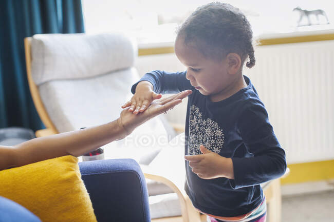 Цікава дівчина торкається руки матері — стокове фото