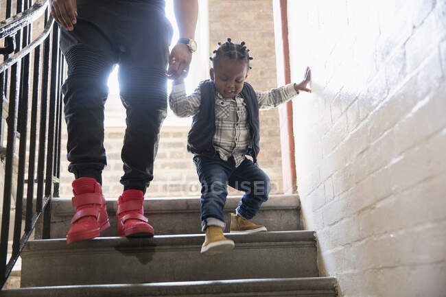Père aidant un jeune garçon descendant un escalier — Photo de stock