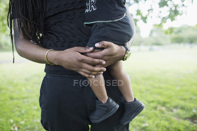 Père tenant un fils tout-petit dans un parc — Photo de stock