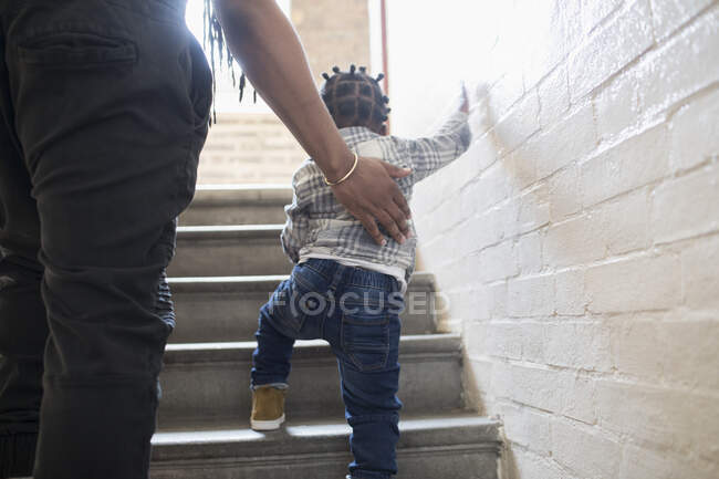 Father helping toddler son climb stairs in stairwell — Stock Photo