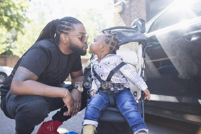 Affectionate father kissing toddler son in stroller — Stock Photo