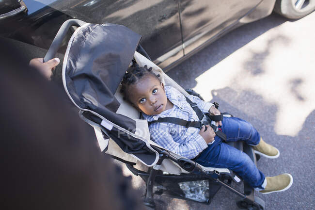 Cute toddler boy in stroller on sidewalk — Stock Photo