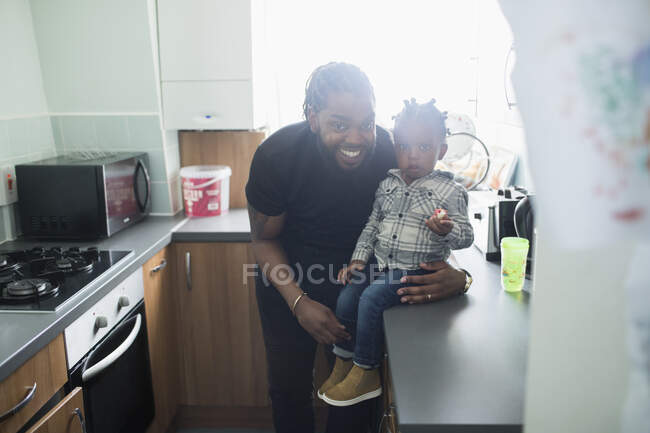 Retrato feliz padre e hijo menor en la cocina de apartamentos. - foto de stock