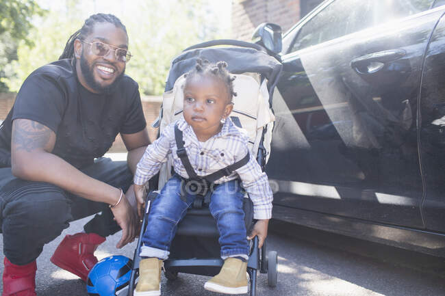Retrato feliz padre con hijo menor en silla de ruedas. - foto de stock