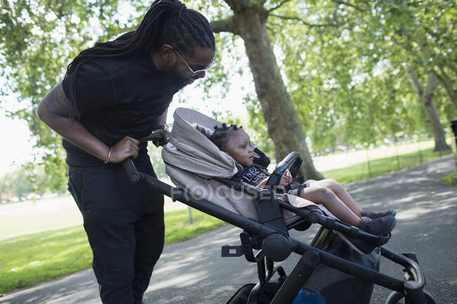 Padre spingendo bambino figlio in passeggino nel parco — Foto stock