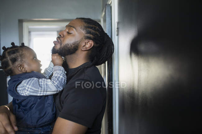 Curieux petit garçon tirant la barbe de son père — Photo de stock