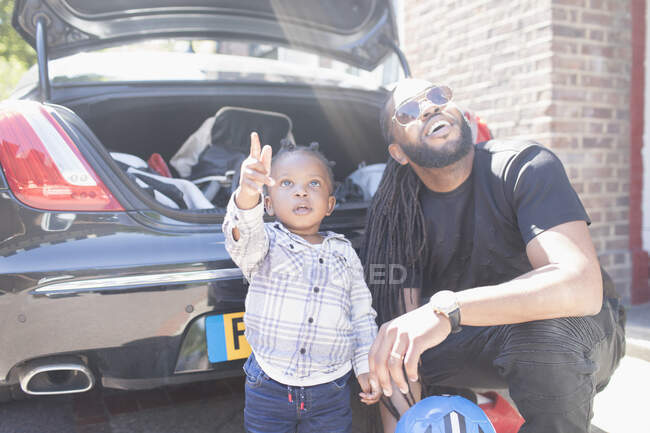 Vater und neugieriger Kleinkind-Sohn schauen hinter Auto auf — Stockfoto