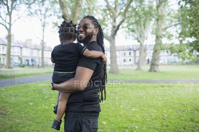 Portrait happy father holding toddler son in park — Stock Photo