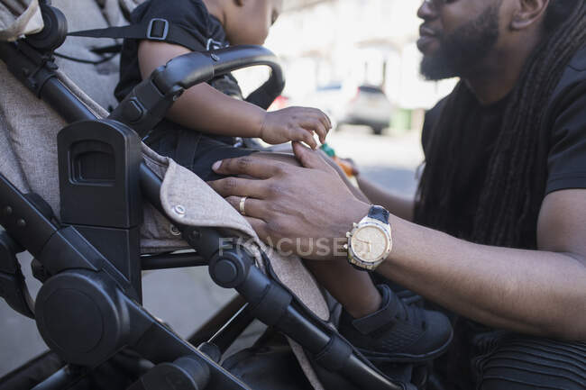 Father talking to toddler son in stroller — Stock Photo