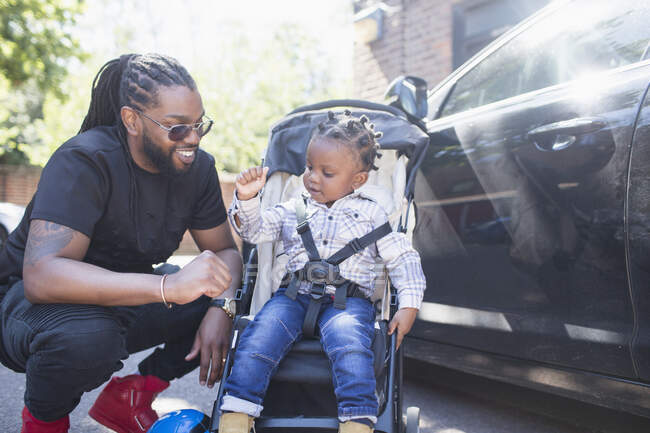 Father fist bumping toddler son in stroller — Stock Photo