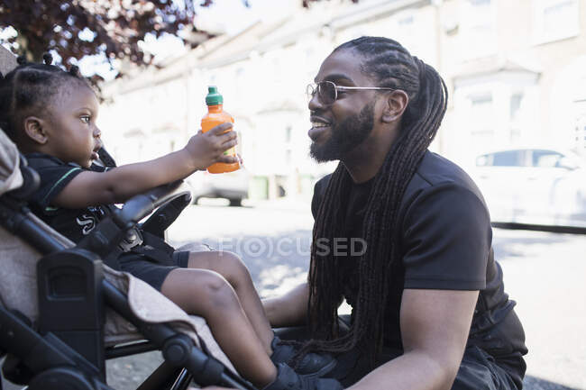 Pai conversando com filho criança em carrinho na calçada urbana — Fotografia de Stock