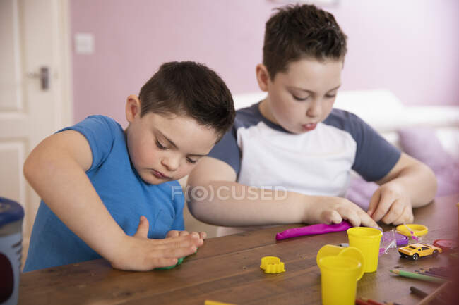 Niño con síndrome de Down y hermano jugando - foto de stock