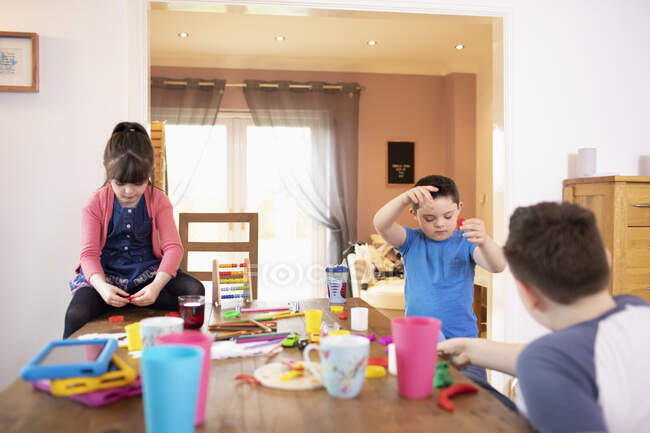 Irmãos e irmã brincando com brinquedos na mesa de jantar — Fotografia de Stock