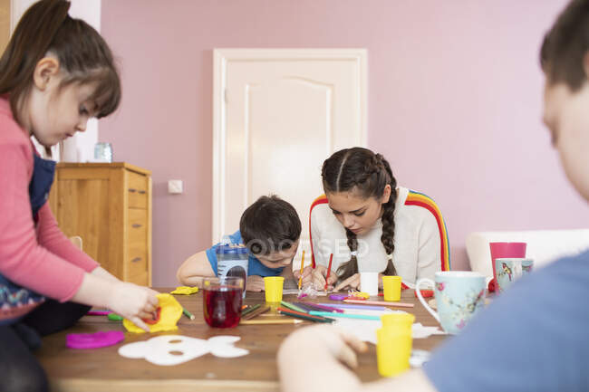 Brothers and sisters coloring at dining table — Stock Photo