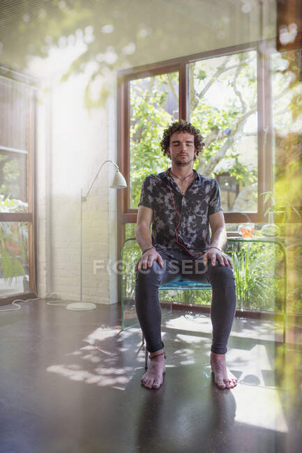 Serene young man meditating in home office — Stock Photo