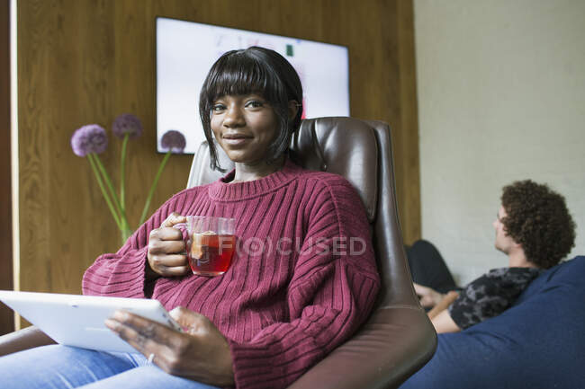 Retrato jovem mulher bebendo chá e usando tablet digital na sala de estar — Fotografia de Stock