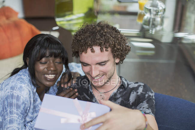 Happy young couple opening gift — Stock Photo