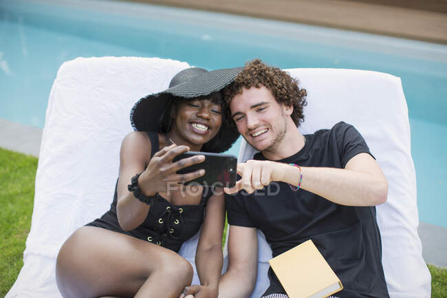 Happy young couple taking selfie with camera phone at poolside — Stock Photo
