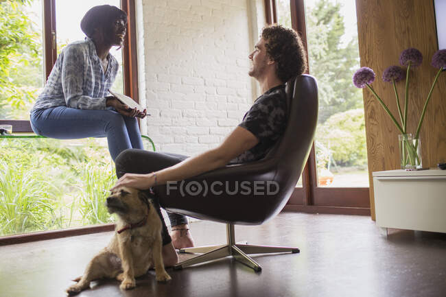 Feliz joven pareja con perro usando tableta digital en la oficina - foto de stock