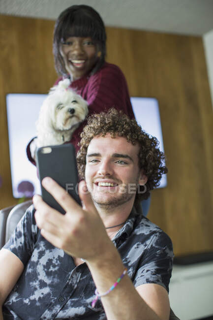Joyeux jeune couple avec chien vidéo bavardage avec téléphone intelligent — Photo de stock
