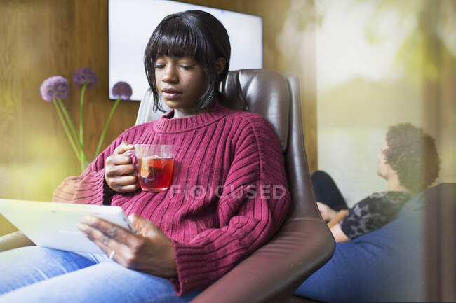 Jovem mulher bebendo chá e usando tablet digital — Fotografia de Stock