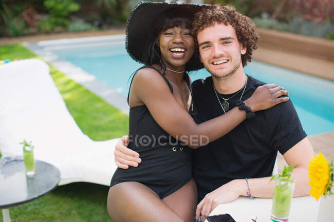 Portrait happy young multiethnic couple relaxing at poolside — Stock Photo