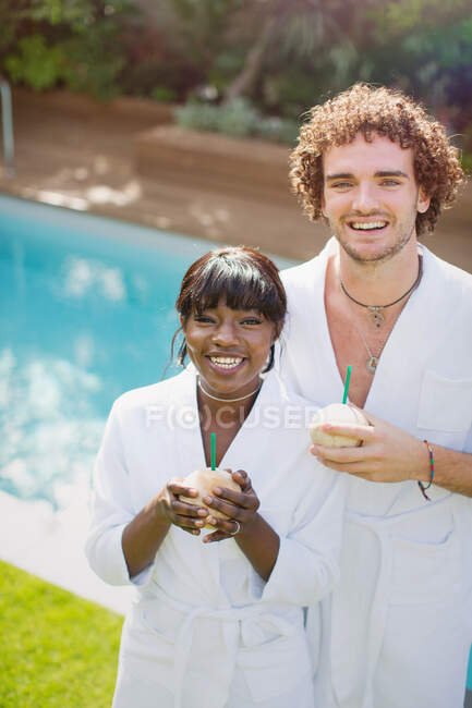 Portrait jeune couple heureux en peignoirs buvant des noix de coco — Photo de stock