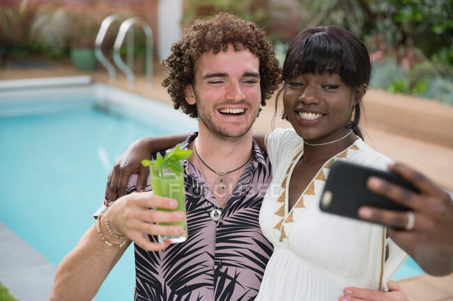Счастливая молодая пара делает селфи с камерой телефона у бассейна — стоковое фото