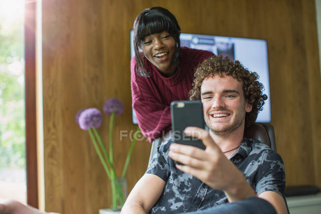 Joyeux jeune couple utilisant un téléphone intelligent — Photo de stock