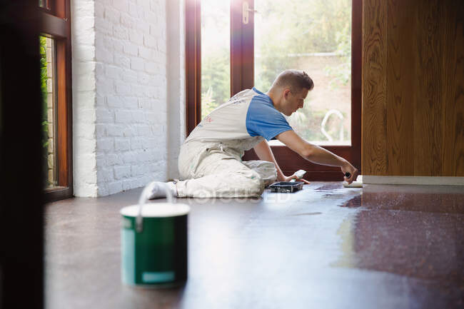 Focused young male construction worker laminating floors at construction site — Stock Photo