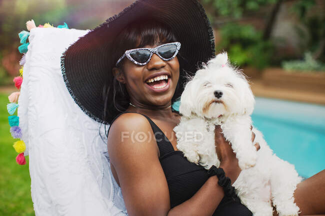 Retrato feliz jovem com cão na beira da piscina — Fotografia de Stock