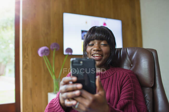 Улыбающаяся молодая женщина с помощью смартфона — стоковое фото