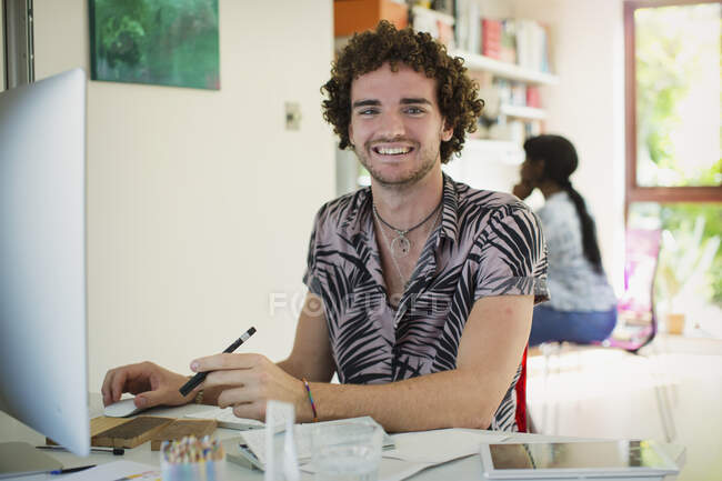 Портрет усміхнений молодий чоловік працює за комп'ютером в домашньому офісі — стокове фото