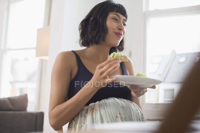Счастливая беременная женщина ест — стоковое фото