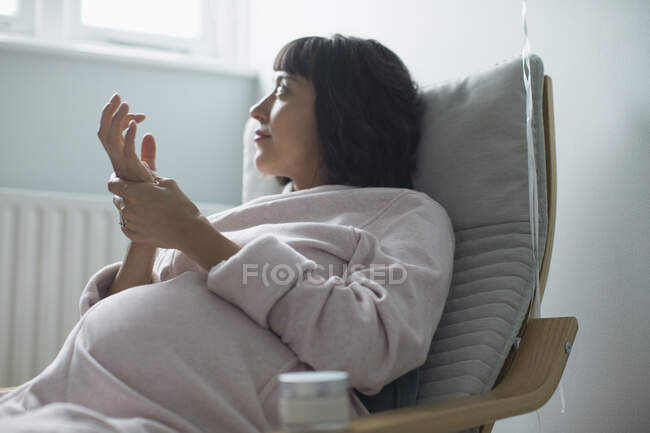 Беременная женщина в халате трёт руки — стоковое фото