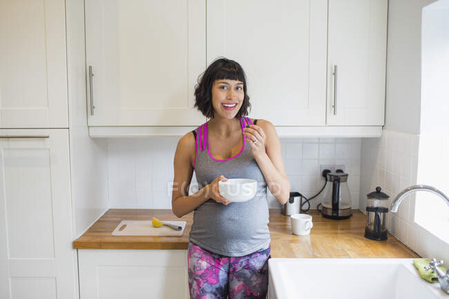 Retrato feliz mujer embarazada comiendo en la cocina — Stock Photo