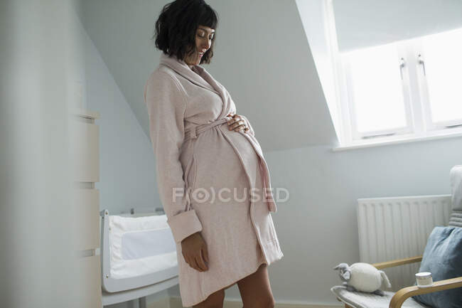 Счастливая беременная женщина в халате массирует желудок — стоковое фото
