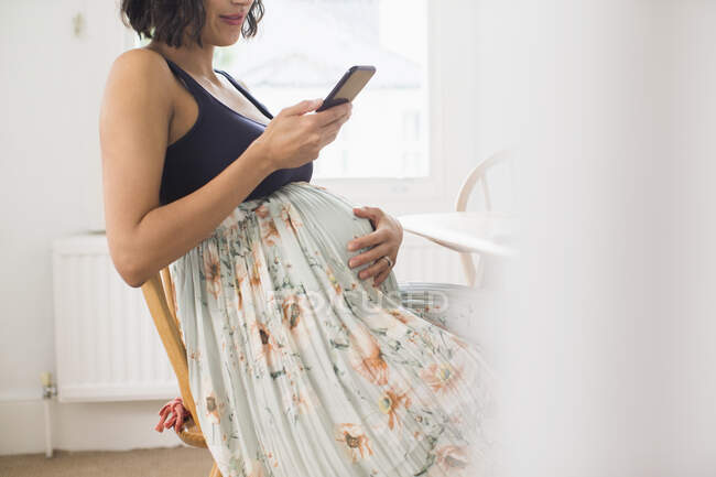 Mulher grávida em saia floral segurando estômago — Fotografia de Stock