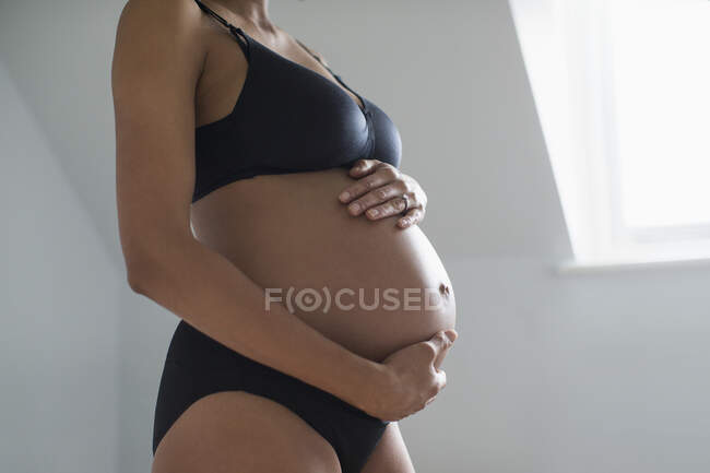Donna incinta in reggiseno e mutandine che tengono lo stomaco — Foto stock