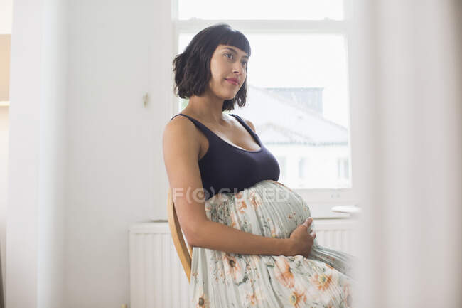 Продумана вагітна жінка тримає живіт — стокове фото