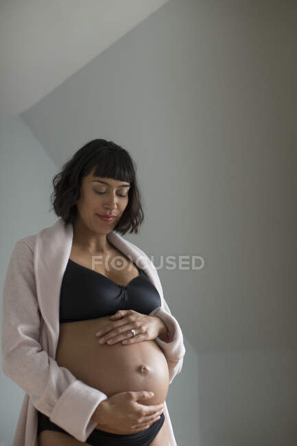 Mulher grávida em sutiã segurando estômago — Fotografia de Stock