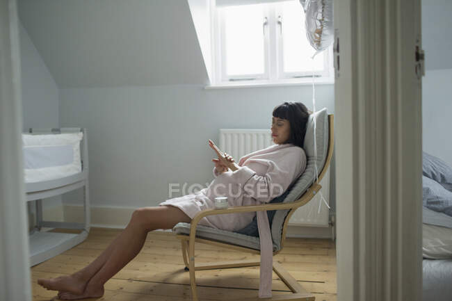 Heitere Schwangere im Bademantel entspannt im Kinderzimmer — Stockfoto
